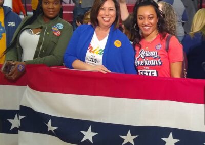Three women stand behind a flag